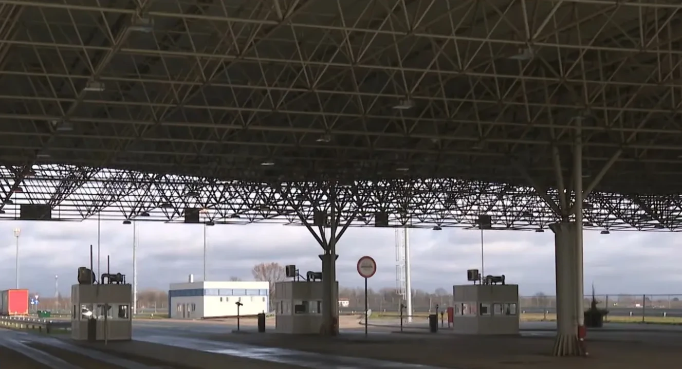 Nadstrešnica na graničnom prelazu sa kontrolnim punktovima i zgradama u pozadini.