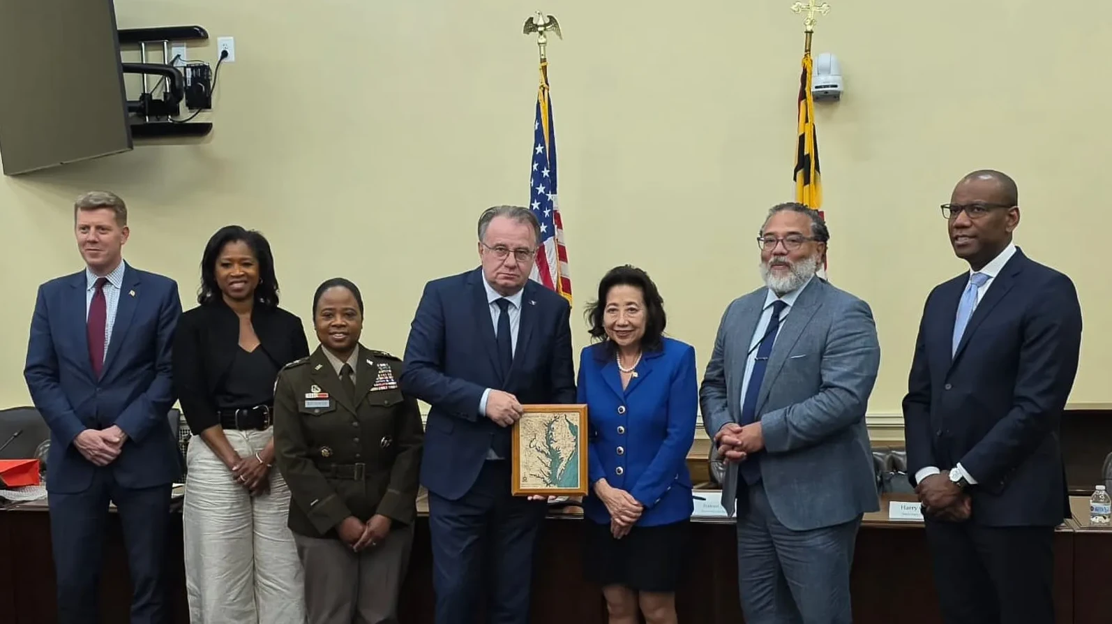 Grupa zvaničnika pozira za fotografiju ispred američke i Merilendske zastave.