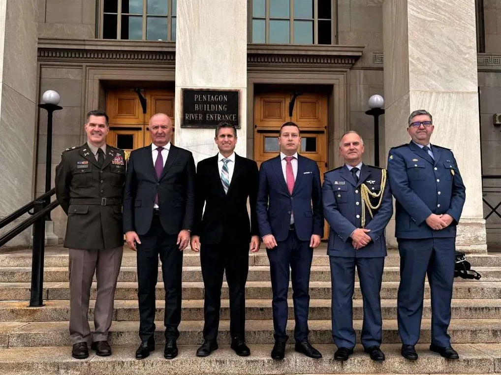 Šestorica muškaraca u uniformama i odijelima stoje na stepenicama ispred zgrade Pentagona, sa natpisom "PENTAGON BUILDING RIVER ENTRANCE"