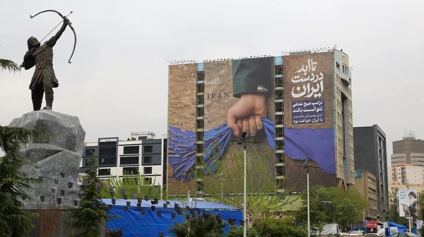 Statua strijelca sa lukom i strijelom ispred zgrade sa velikim plakatom na kojem piše "IRAN" i perzijski natpis.