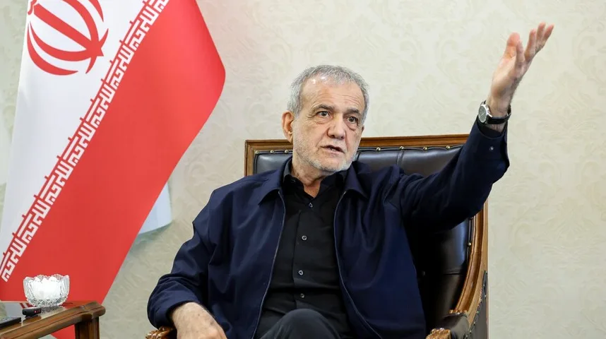 Iranski političar sjedi u fotelji pored zastave Irana i gestikulira rukom.