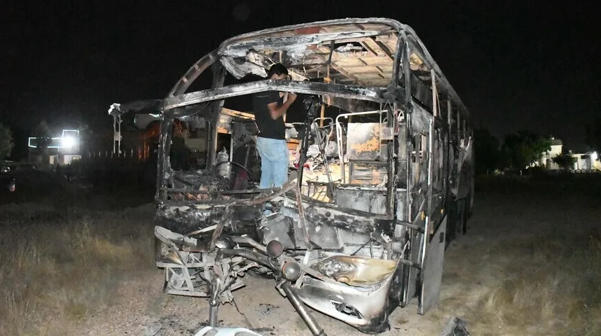Izgorjeli autobus u noćnim uslovima, sa vidljivim oštećenjima i dijelovima konstrukcije.