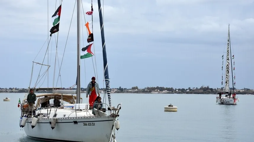Jedrilica sa palestinskim zastavama na jarbolu plovi mirnim morem, sa još jednom jedrilicom u pozadini.