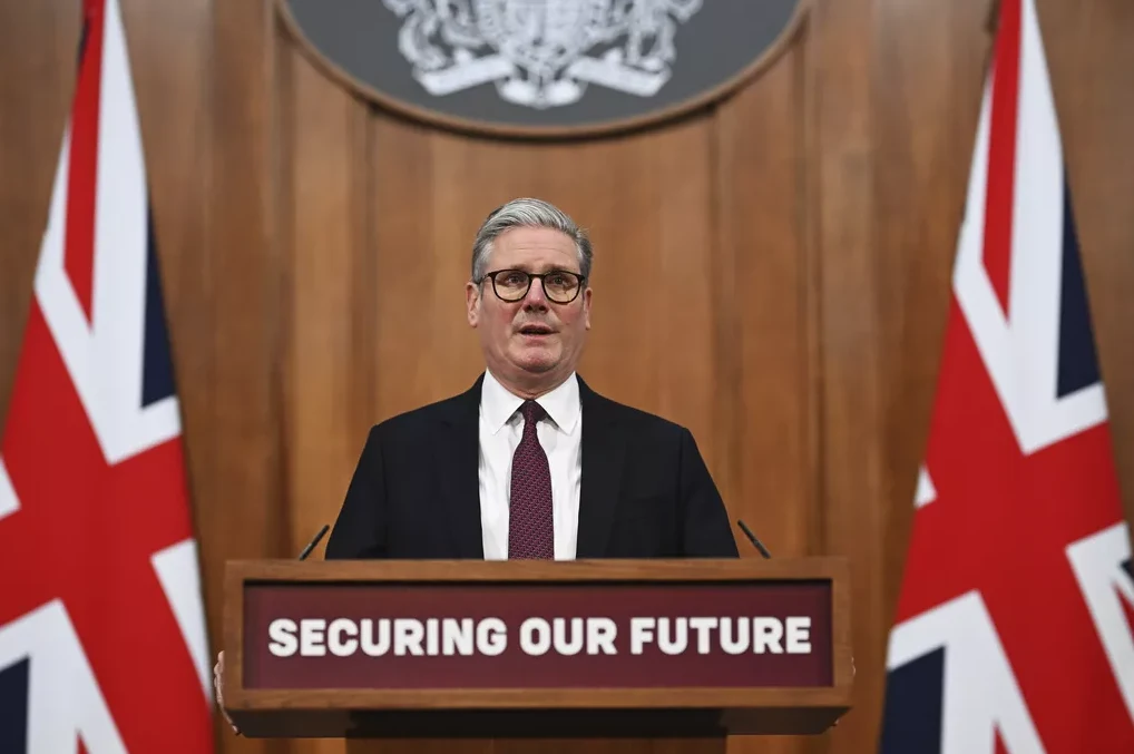 Kier Starmer govori iza govornice sa natpisom "Securing Our Future", sa britanskim zastavama sa obje strane.