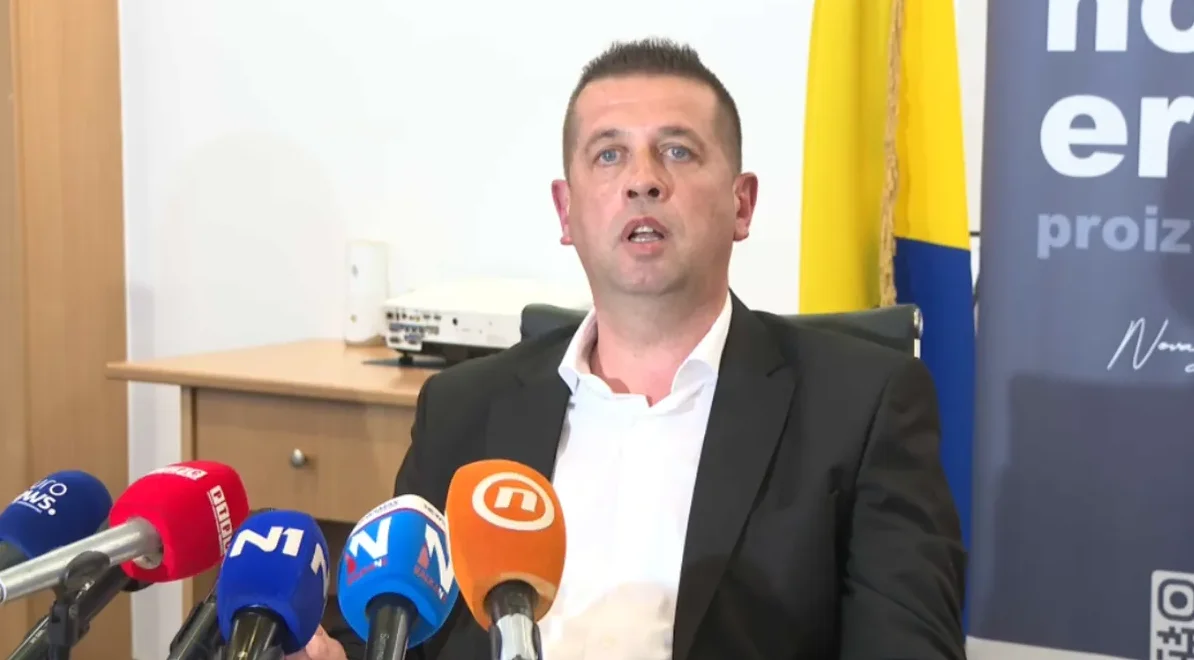 Muškarac u crnom odijelu govori za govornicom, okružen sa nekoliko mikrofona medijskih kuća poput N1, Nova BH i BHT1.