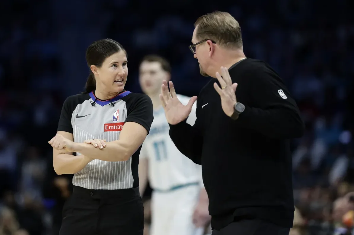 Ženska košarkaška sutkinja sa pruženim rukama prema košarkaškom treneru