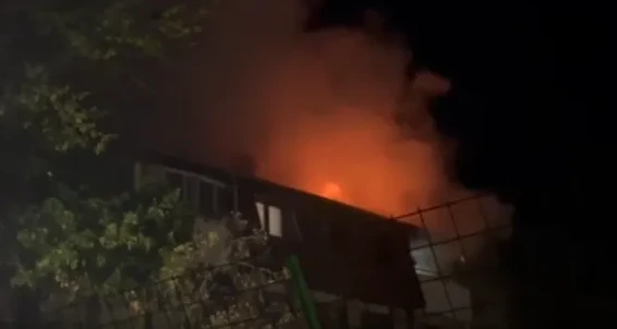 Kuća zahvaćena plamenom i gustim dimom noću.