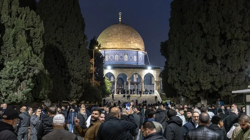 Grupa ljudi stoji ispred Kupole na stijeni u Jeruzalemu noću, neki fotografišu objekt.