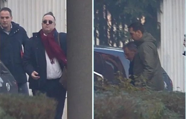 Dva muškarca u odijelima i jednom kaputu sa maramom, dok ih drugi muškarac prati.