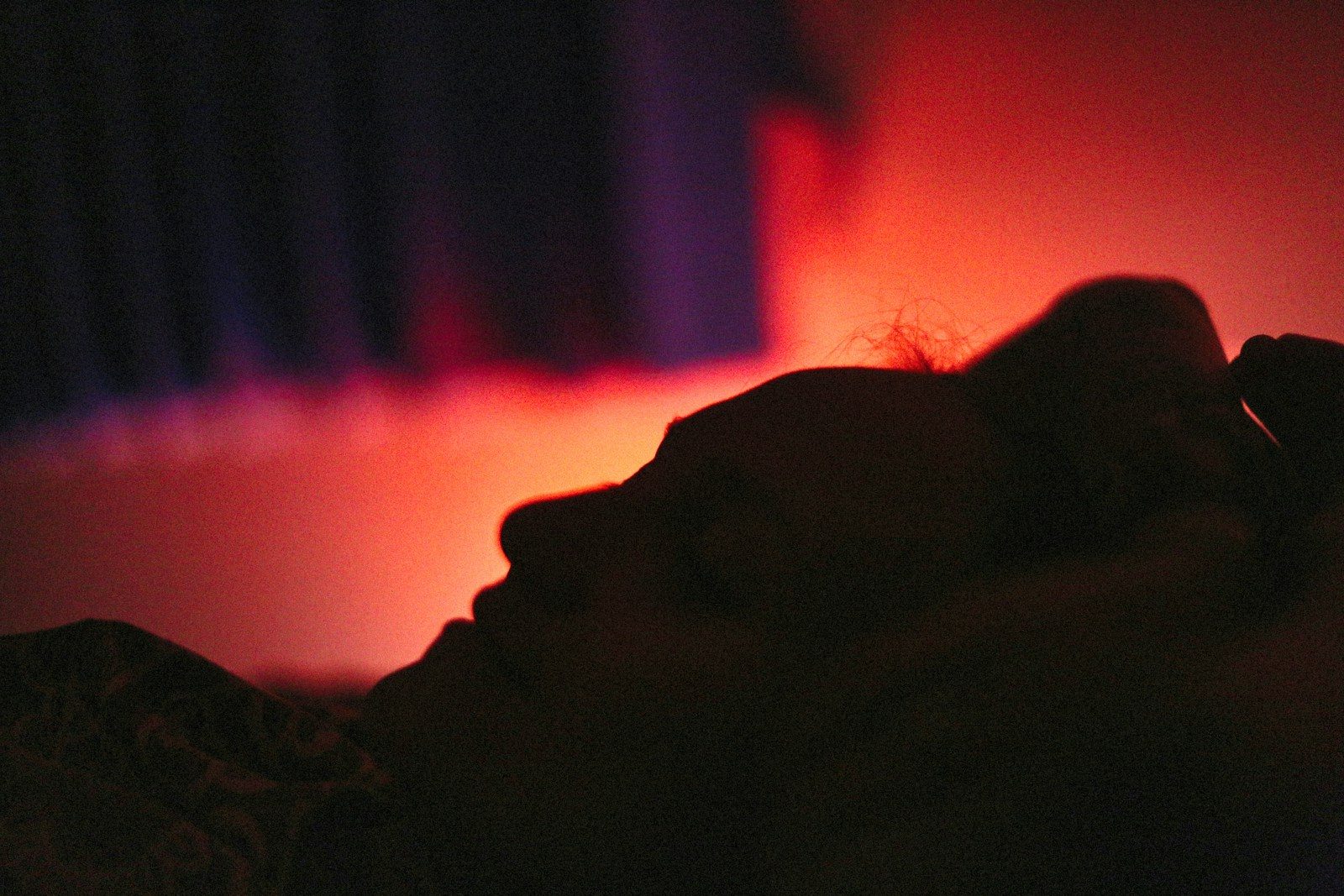 A silhouette of a person bathed in red light.