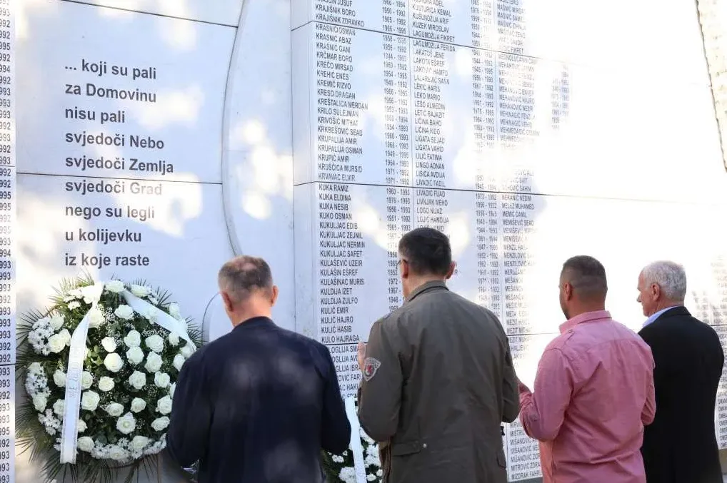 Ljudi ispred spomen-ploče sa imenima poginulih