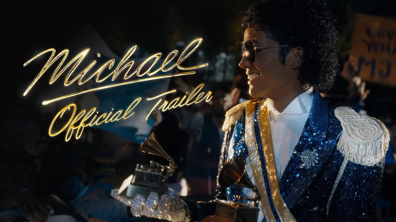 Michael Jackson u blistavom plavo-zlatnom sakou drži Grammy nagrade, naslov "Michael Official Trailer" ispisan zlatnim slovima.