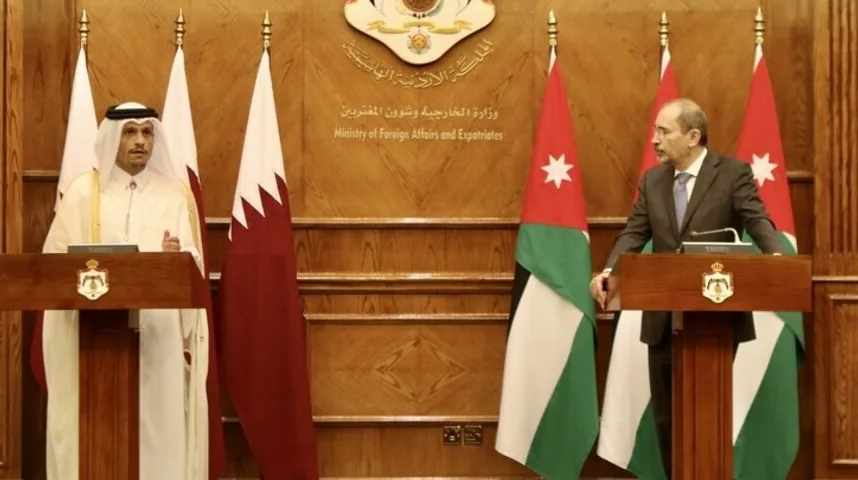 Dva zvaničnika, jedan u tradicionalnoj katarskoj odjeći, a drugi u odijelu, stoje iza govornica ispred zastava Katara i Jordana.