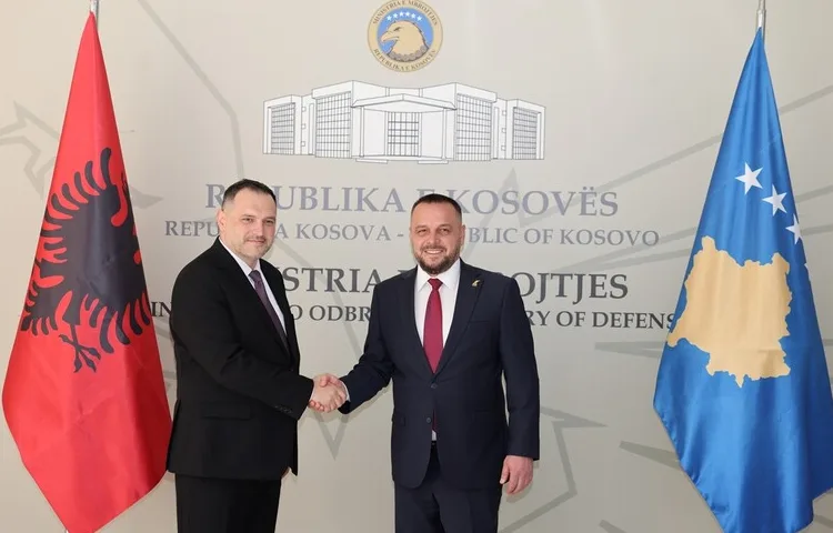 Dvojica muškaraca u odijelima rukuju se ispred zastava Kosova i Albanije.