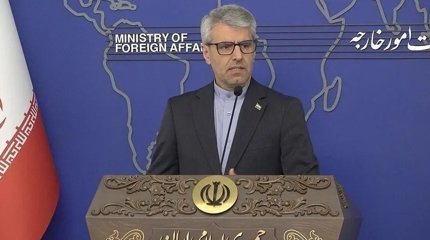 Muškarac u odijelu i naočalama stoji iza govornice sa grbom Irana, a u pozadini je logo Ministarstva vanjskih poslova Irana.