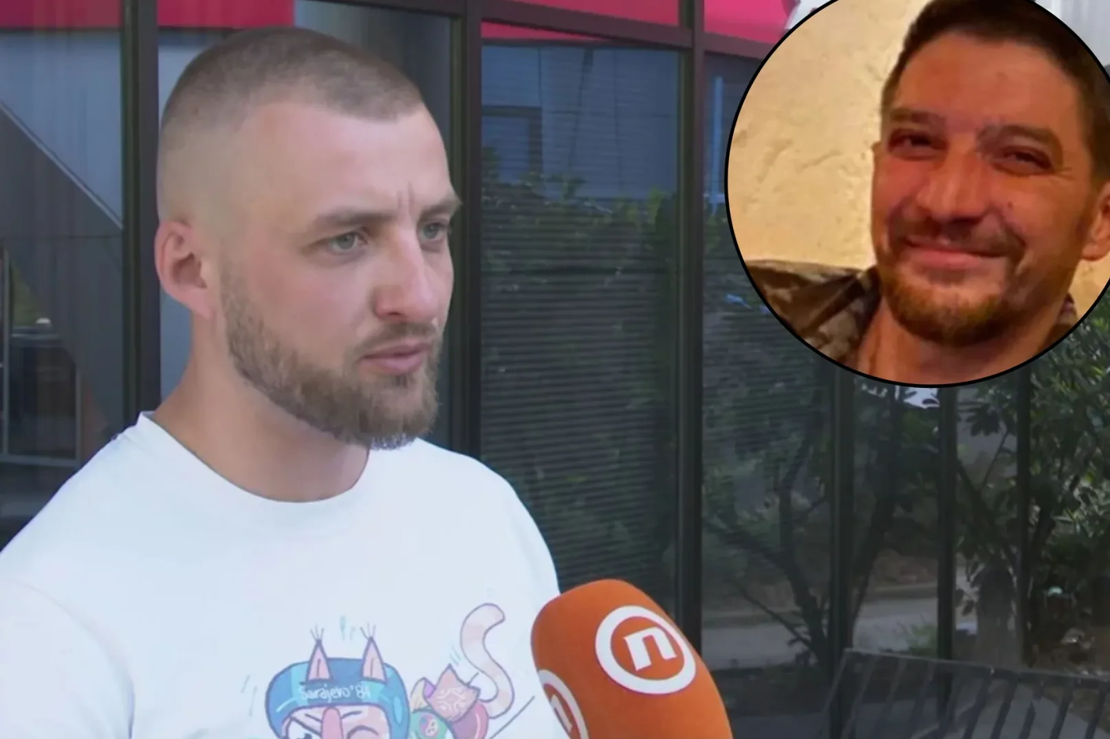 Mladić sa kratkom kosom i bradom, obučen u bijelu majicu sa printom, govori u narandžasti mikrofon sa logom N1 televizije. U gornjem desnom uglu fotografije je kružno izrezana fotografija muškarca, pretpostavlja se poginulog vojnika, kako se smješka.