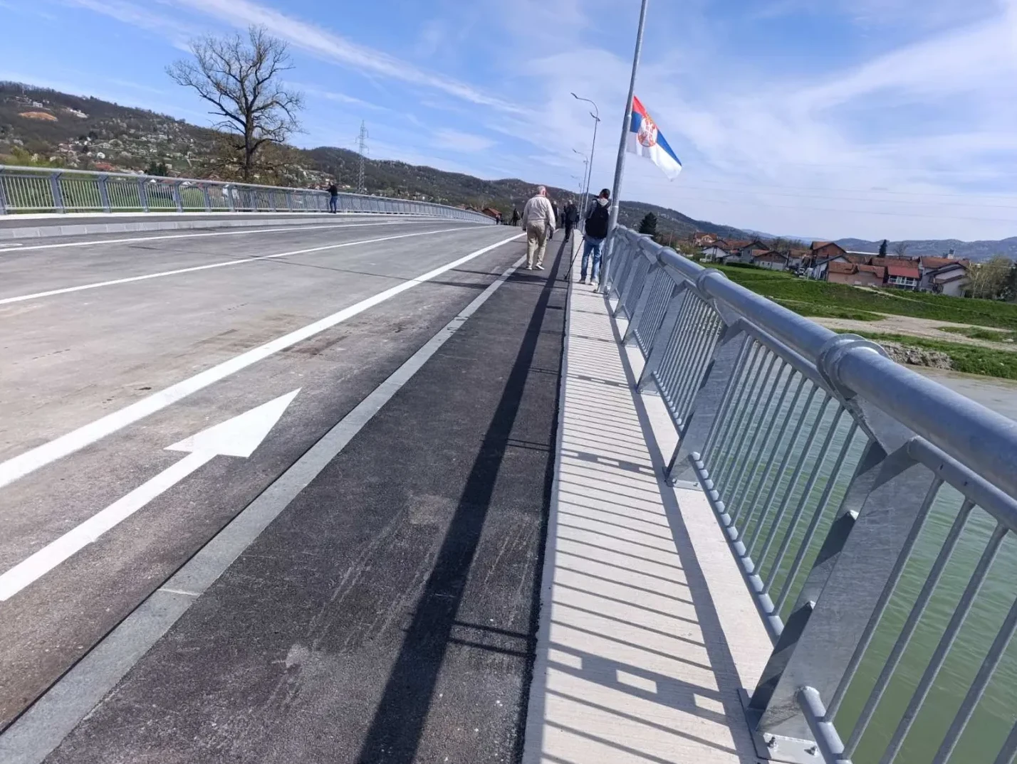 Novi most sa pješačkom stazom i biciklističkom trakom, ograda od metala, te srpska zastava na vrhu.
