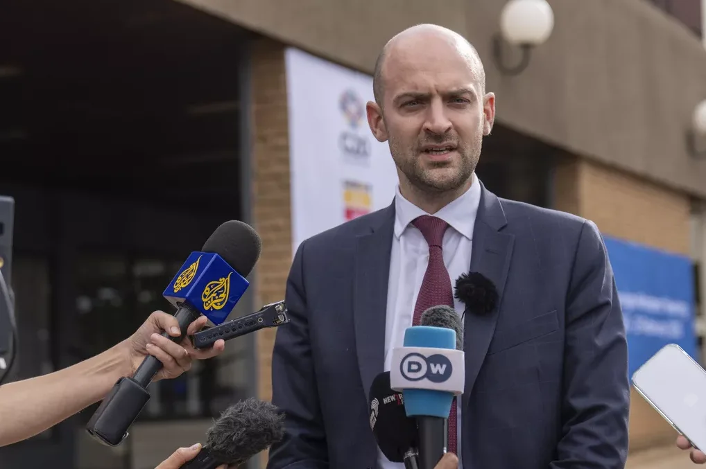 Muškarac u tamnom odijelu sa crvenom kravatom daje izjavu novinarima ispred zgrade.