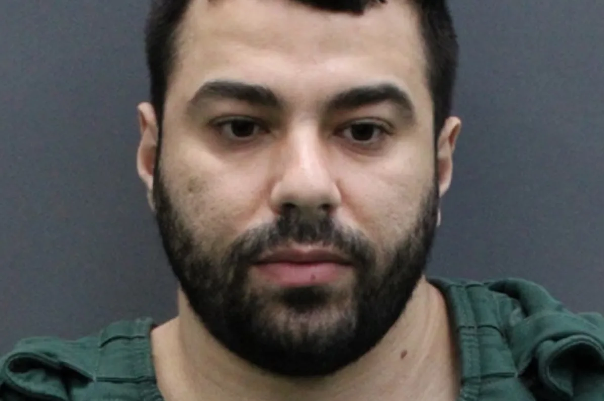 Portret muškarca sa kratkom tamnom kosom, naglašenim obrvama, brkovima i bradom.