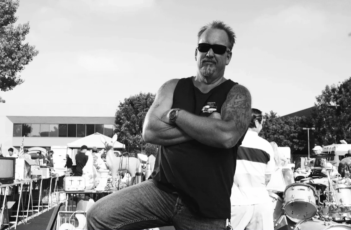 Muškarac sa tetovažama i naočarima kroji ruke