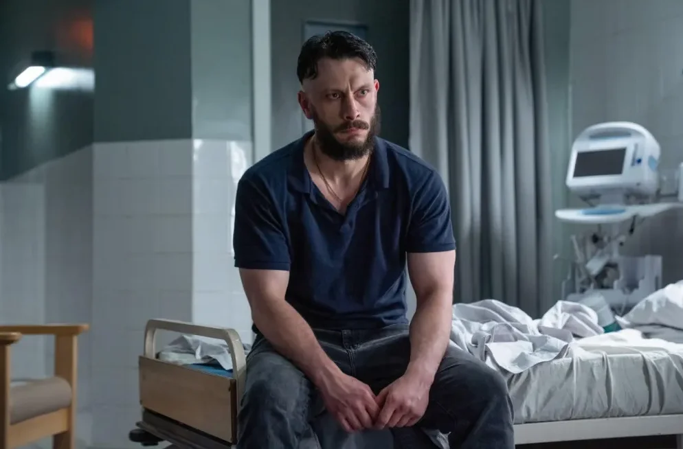Muškarac sa bradom sjedi na bolničkom krevetu