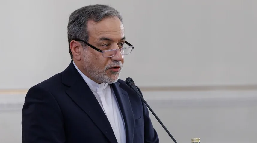 Muškarac u tamnom odijelu i bijeloj košulji, sa naočalama i prosijedom bradom, govori u crni mikrofon.