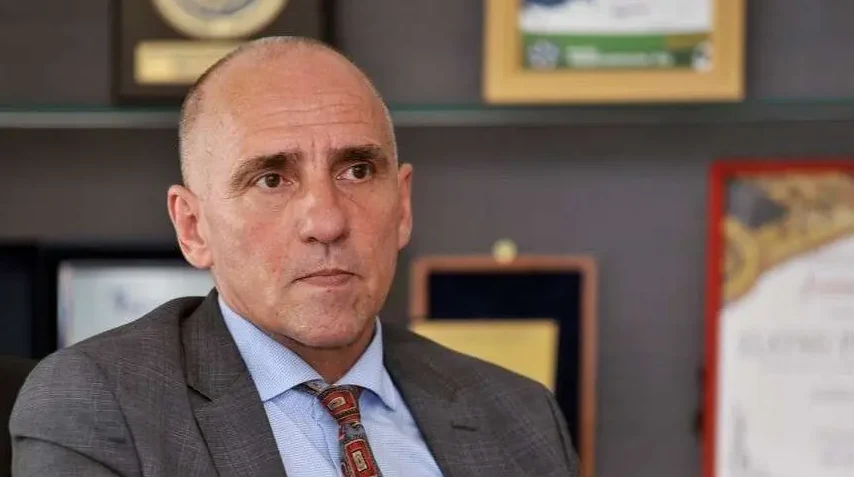 Portret muškarca u tamnom odijelu i plavoj košulji s kariranom kravatom, fokus je na licu