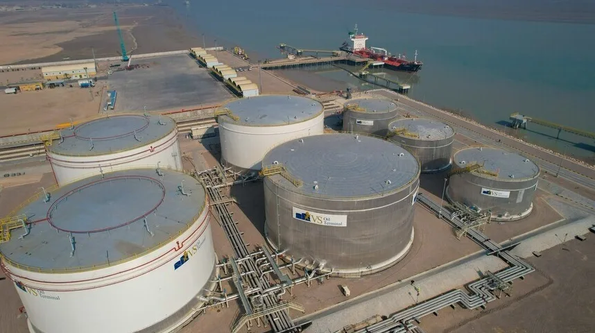Aerialni pogled na veliki naftni terminal sa skladišnim rezervoarima i brodom na pristaništu.