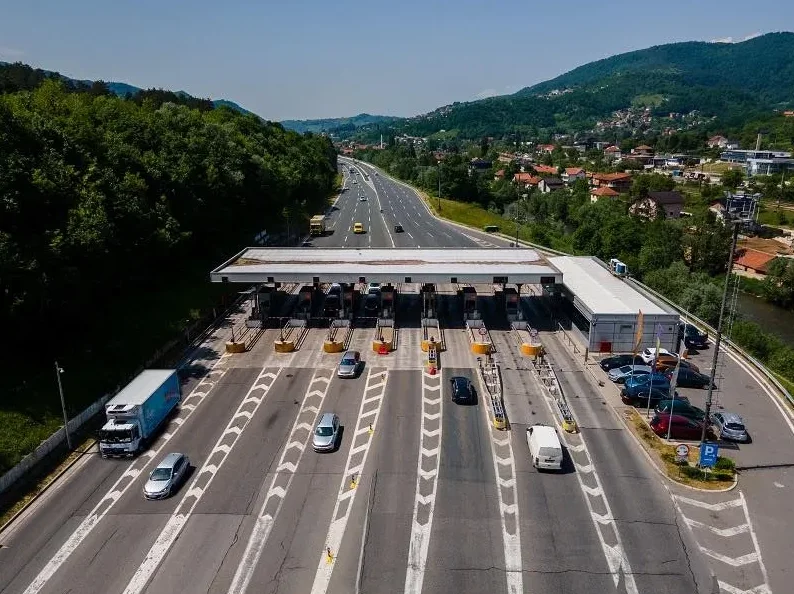 Naplatna rampa na autoputu sa više traka za naplatu i vozilima u prolazu.