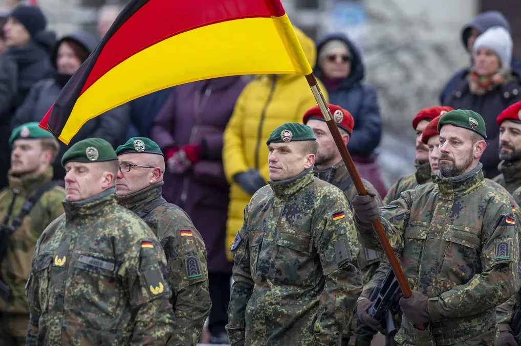 Vojnici u njemačkim uniformama sa zelenim beretkama i njemačkom zastavom tokom parade.