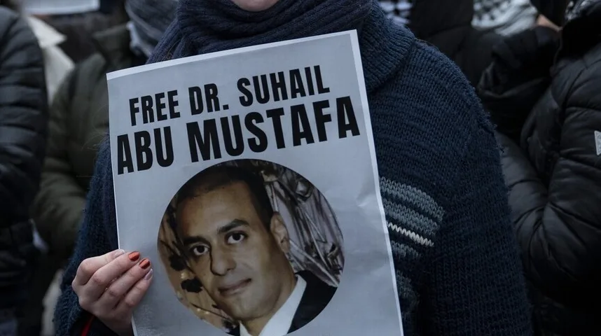 Držeći poster sa slikom i natpisom "FREE DR. SUHAIL ABU MUSTAFA"