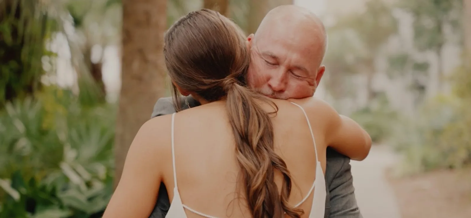 Otac nježno grli svoju kćerku, sa zatvorenim očima, na njen dan vjenčanja, dok ona nosi vjenčanicu.