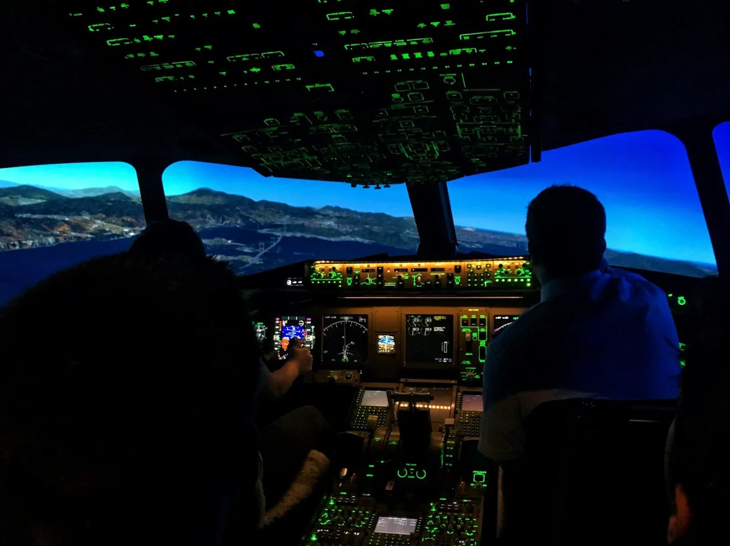 Pogled iz pilotske kabine simulatora leta na instrumente i ekran koji prikazuje pejzaž.