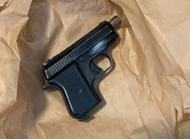 Crni pištolj marke Zastava leži na smeđem papiru.