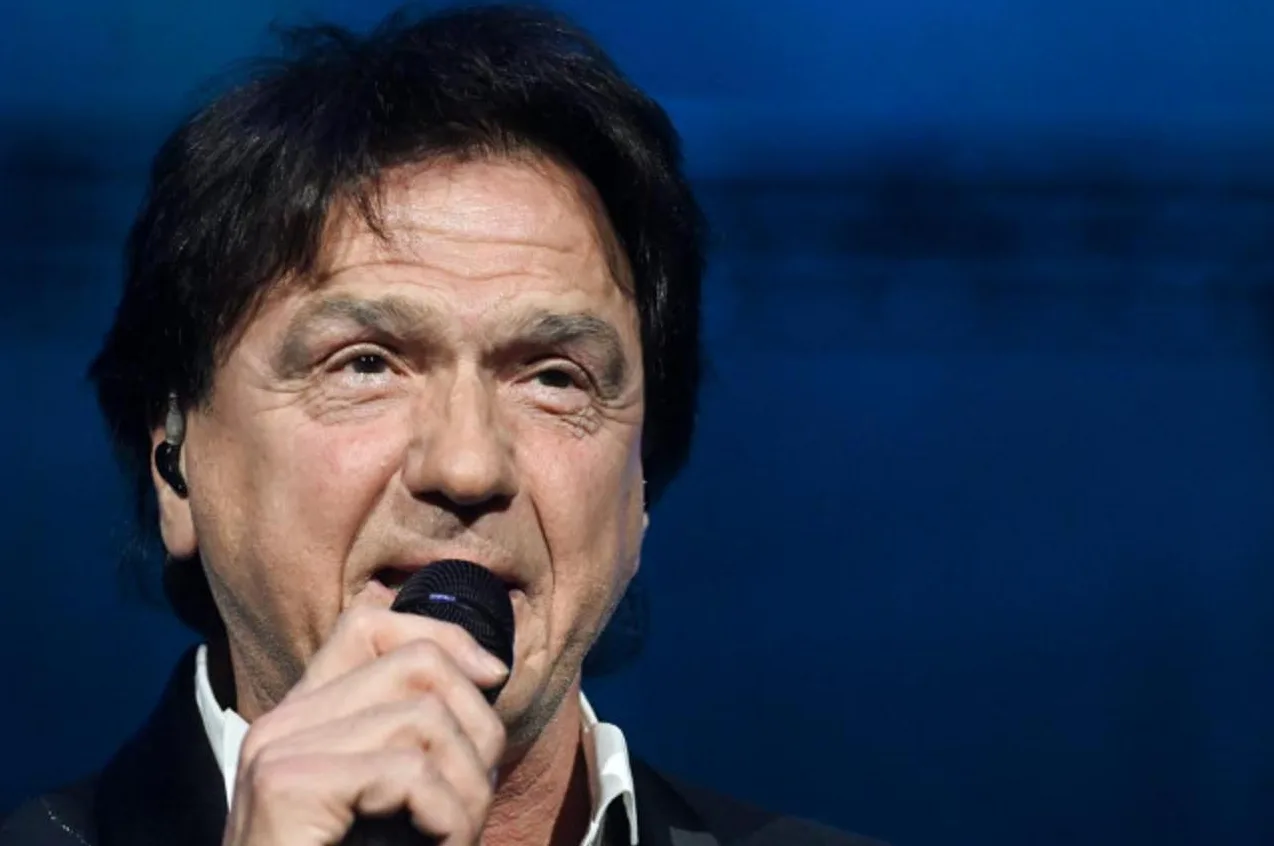 Portret poznatog pjevača kako pjeva na pozornici sa mikrofonom u ruci.