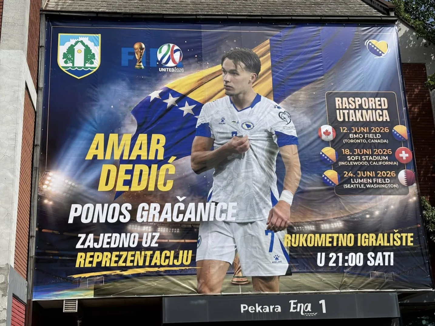 Veliki plakat s likom fudbalera Amara Dedića, koji predstavlja ponos Gradačca i podršku reprezentaciji Bosne i Hercegovine. Prikazan je raspored utakmica reprezentacije za 2026. godinu, uključujući datume i lokacije igranja utakmica.