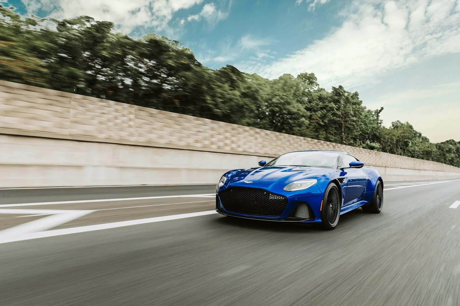 Plavi Aston Martin DBS Superleggera u pokretu na autoputu.