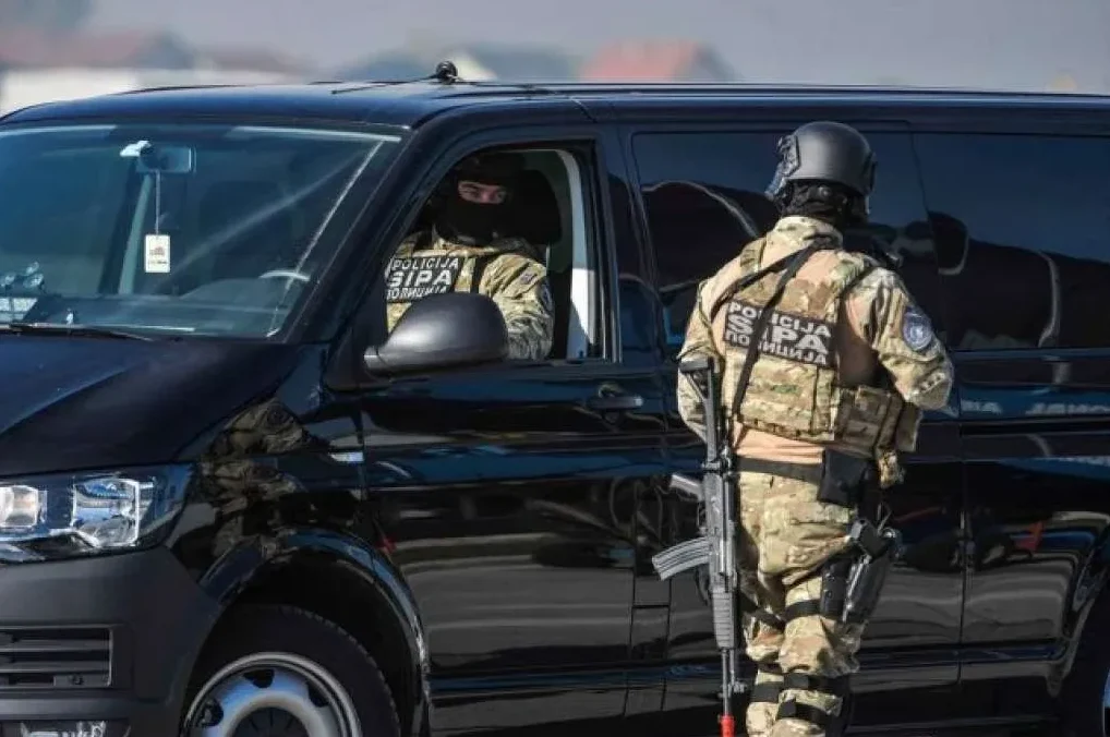 Policajci SIPA-e u punoj opremi, jedan sjedi u crnom kombiju, drugi stoji pored njega.