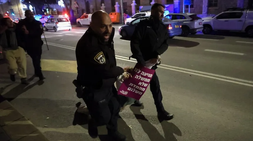 Policajci u uniformama odvode osobu koja drži transparent na kojem piše "Ne dajemo vladu koja ne brine o miru".