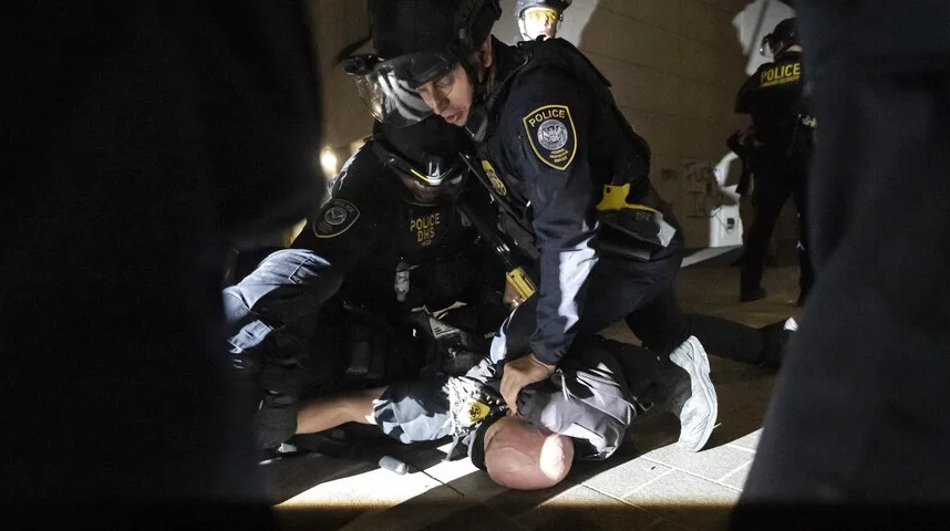 Policijski službenici u opremi savladavaju osobu na tlu.