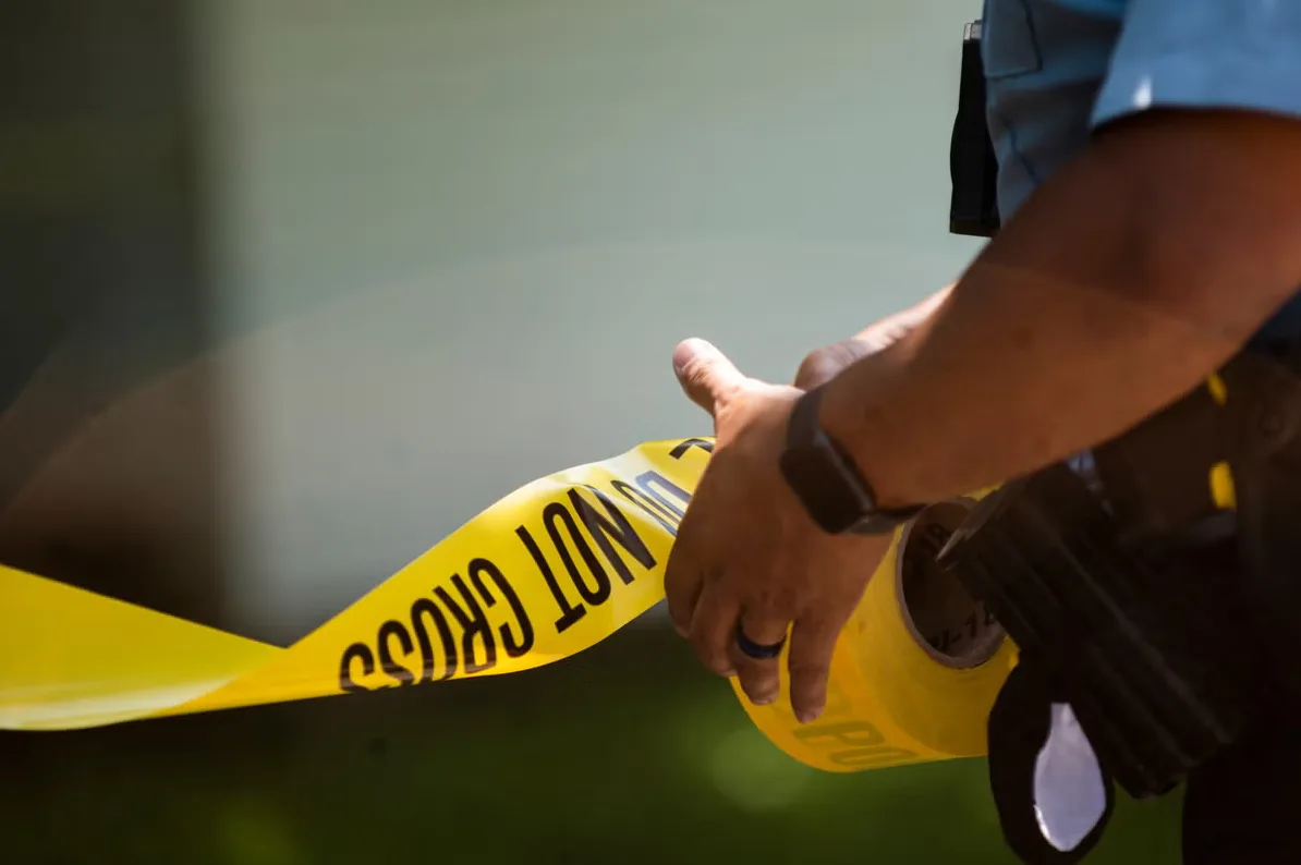 Policajac postavlja žutu traku sa natpisom "Do Not Cross"