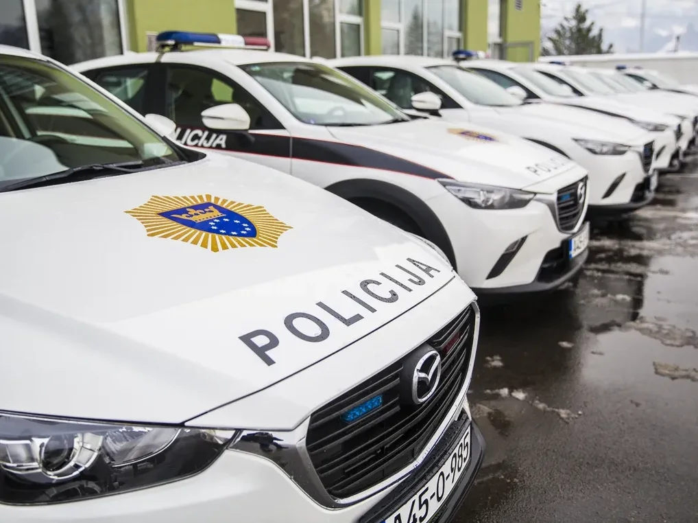Bijela policijska vozila marke Mazda parkirana u redu ispred zgrade.
