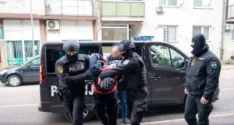 Policijski službenici u punoj opremi vrše privođenje osumnjičenog lica.