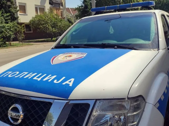 Detalj prednjeg dijela policijskog vozila marke Nissan, sa ispisanim natpisom "POLICIJA" na plavoj podlozi.