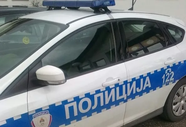 Bijelo policijsko vozilo s plavom trakom na kojoj piše "ПОЛИЦИЈА" i brojem "122".
