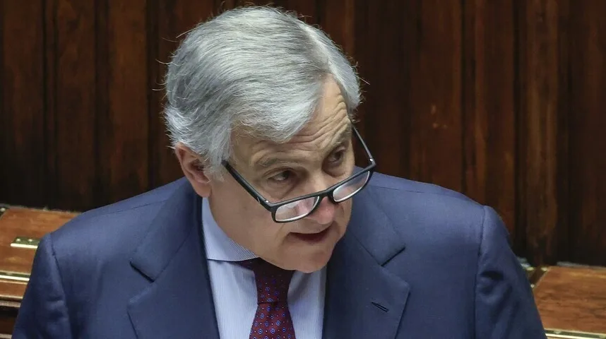 Portret starijeg gospodina sa sijedom kosom i naočarima, obučenog u tamnoplavo odijelo i crvenu kravatu, kako govori.