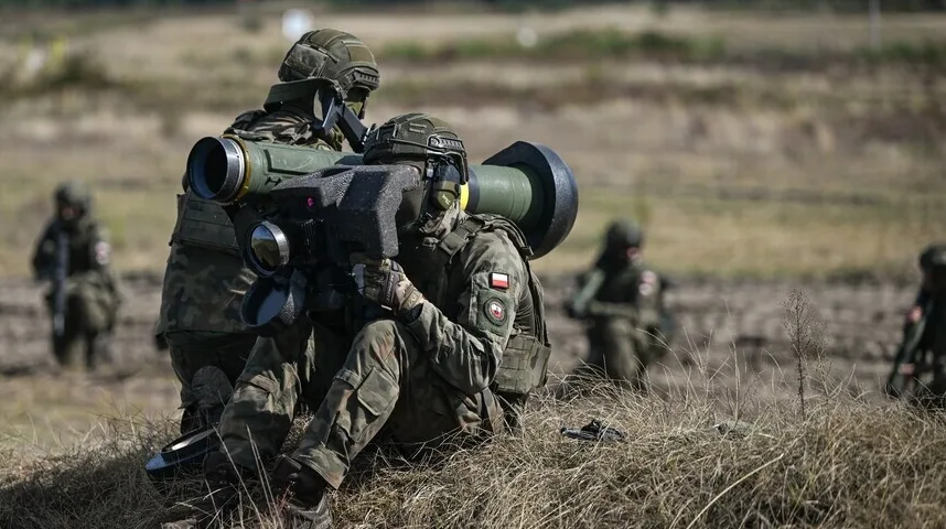 Dva poljska vojnika u punoj ratnoj opremi vježbaju gađanje iz prenosive raketne opreme za navođenje protiv tenkovskih projektila na polju.