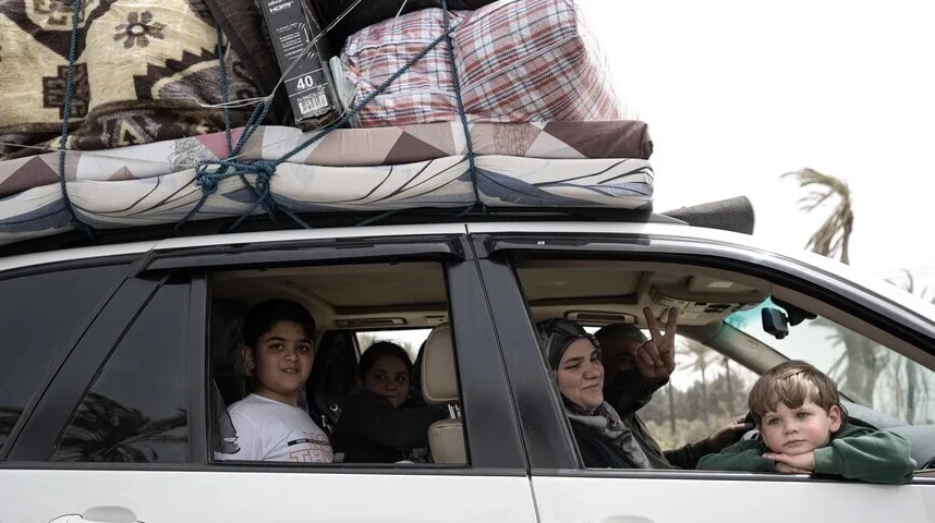 Porodica putuje automobilom natovarenim prtljagom na krovu, s djecom koja gledaju kroz prozore.