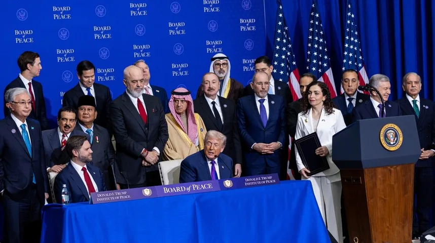Donald Trump sjedi za stolom ispred natpisa "BOARD of PEACE", okružen sa liderima raznih zemalja i američkim zastavama.