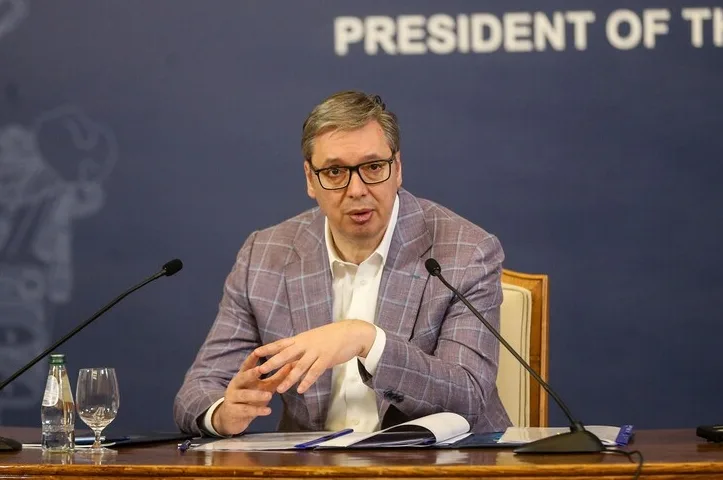 Aleksandar Vučić, predsjednik Srbije, sjedi za stolom ispred mikrofona i papira